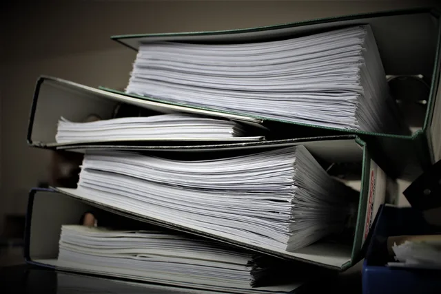 Close-up of stacked binders filled with documents for office or educational use. Tutoring center equipment checklist: three lists