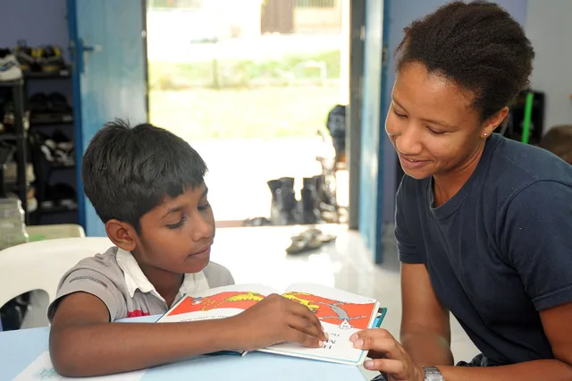 KUALA LUMPUR, Malaysia (Oct. 8, 2012) Operations Specialist 2nd Class Janis Jackson, assigned to the Arleigh Burke-class guided-missile destroyer USS McCampbell (DDG 85), tutors a child on reading English during a community service project at Trinity Community Children’s Center in Kuala Lumpur, Mala. Tutoring center hiring around the after-school shift