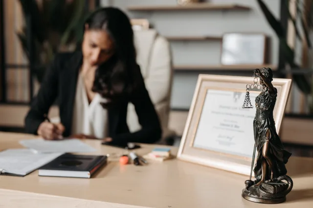 Focused woman writing at desk with Lady Justice figurine and certificate in office. Which permits a tutoring center needs before opening, explained